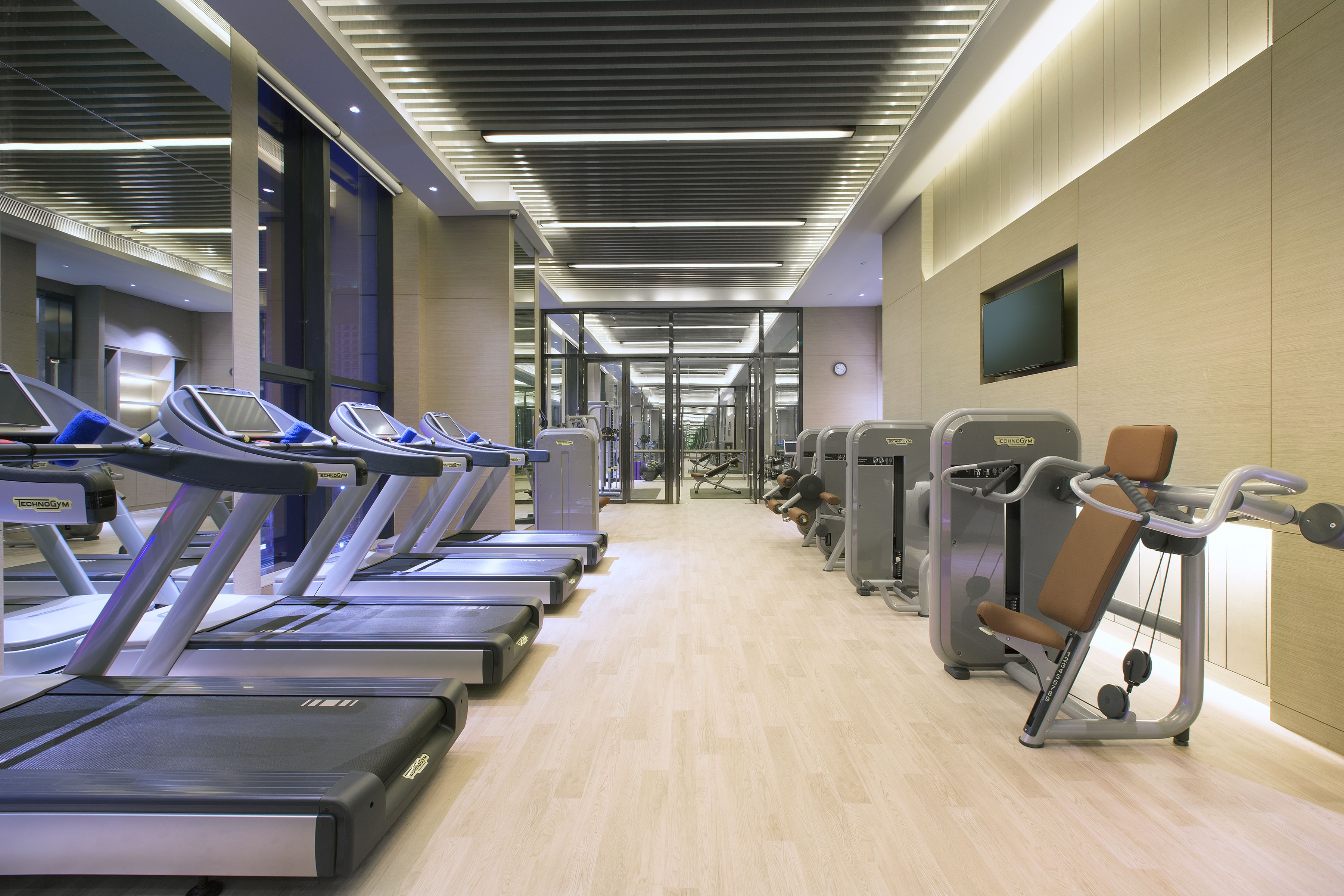 Un gimnasio con cintas de correr, elípticas y equipo de pesas.