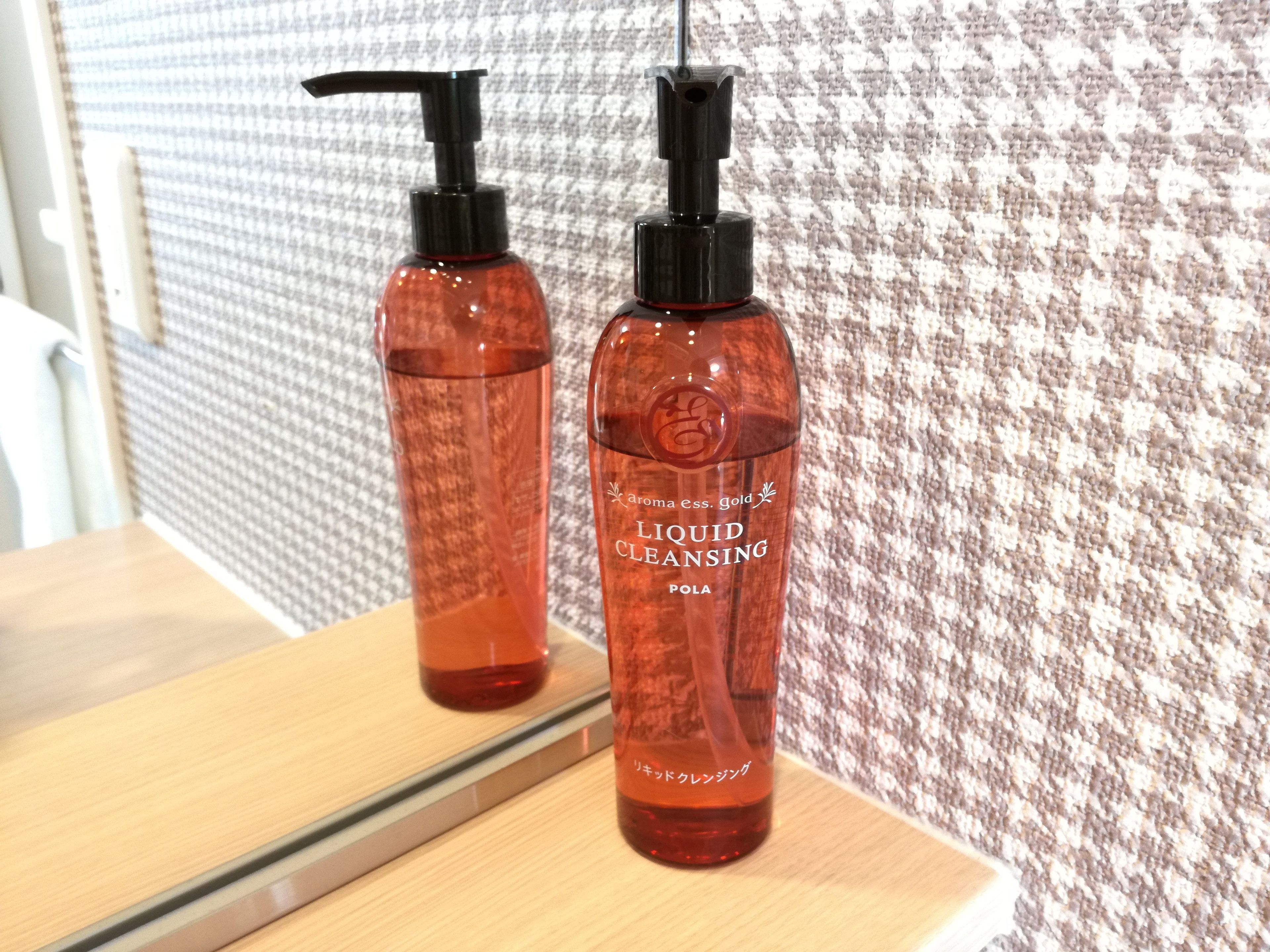Two bottles of liquid cleansing on a wooden surface with a patterned wall in the background.