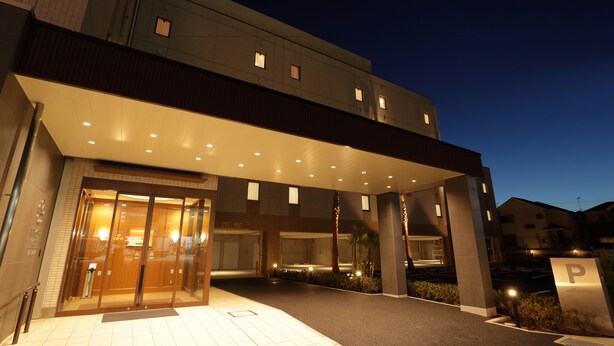A modern hotel entrance with a covered walkway, glass doors, and a parking sign. - Hiyori Hotel Maihama (Urayasu)