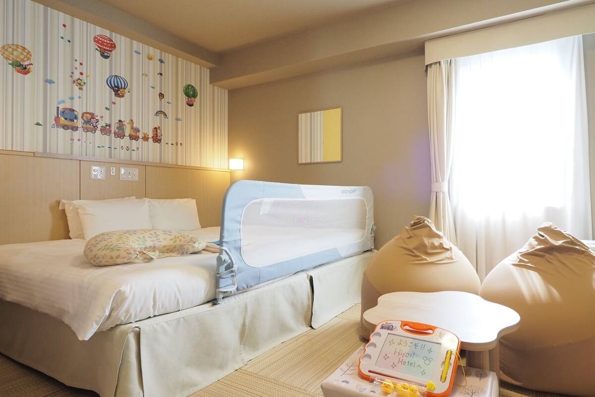 Ein Hotelzimmer mit Bett, Schreibtisch, Sitzsack und einem Fenster mit Vorhängen.