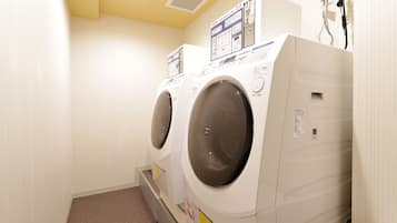 A laundry room with two front-loading washing machines and a dryer.
