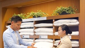 A hotel room with neatly arranged bedding and a wooden shelf with potted plants. - Hiyori Hotel Maihama (Urayasu)
