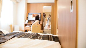 A hotel room with a bed, a desk, a television, and a view of the hallway. - Hiyori Hotel Maihama (Urayasu)