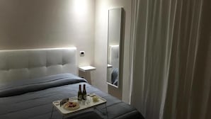 Een moderne hotelkamer met een groot bed, nachtkastje, spiegel en een dienblad met eten en drinken.