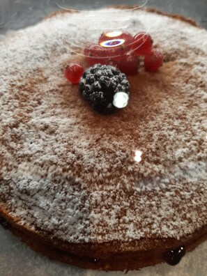 A dessert with powdered sugar, a berry, and a chocolate piece on a plate. - Hotel Alabama (Rimini)