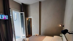 A hotel room with a bed, a TV, and a door leading to a balcony. - Hotel Alabama (Rimini)