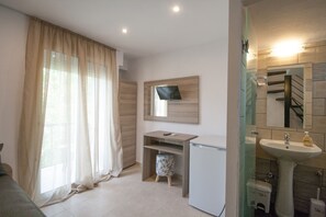 A modern bathroom with a sink, mirror, and toilet. There is a small stool and a television mounted on the wall. - Pension Avocado (Skiathos)