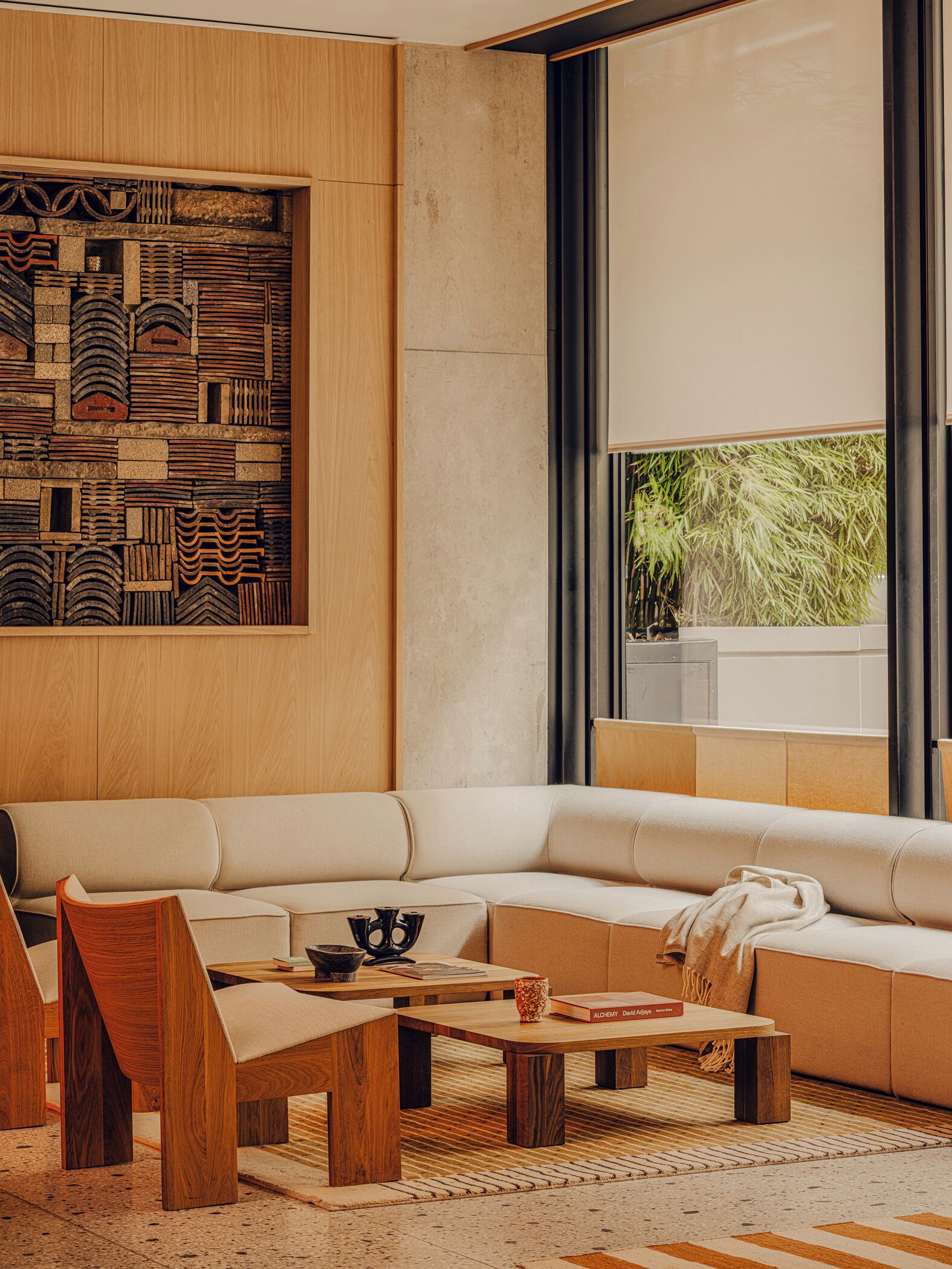 A modern living room with a sectional sofa, wooden coffee table, and a decorative wall panel.