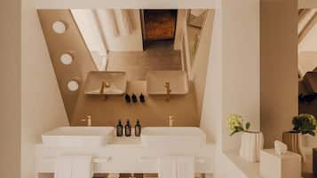 Un baño moderno con tocador doble, un espejo grande y techo inclinado de madera.