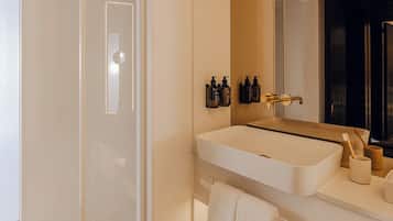 Un baño moderno con un espejo grande, un lavabo blanco y una zona de ducha.