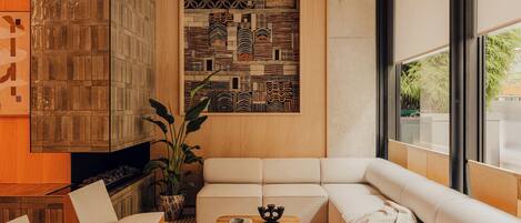 A modern living room with a sofa, two wooden coffee tables, and a patterned wall.
