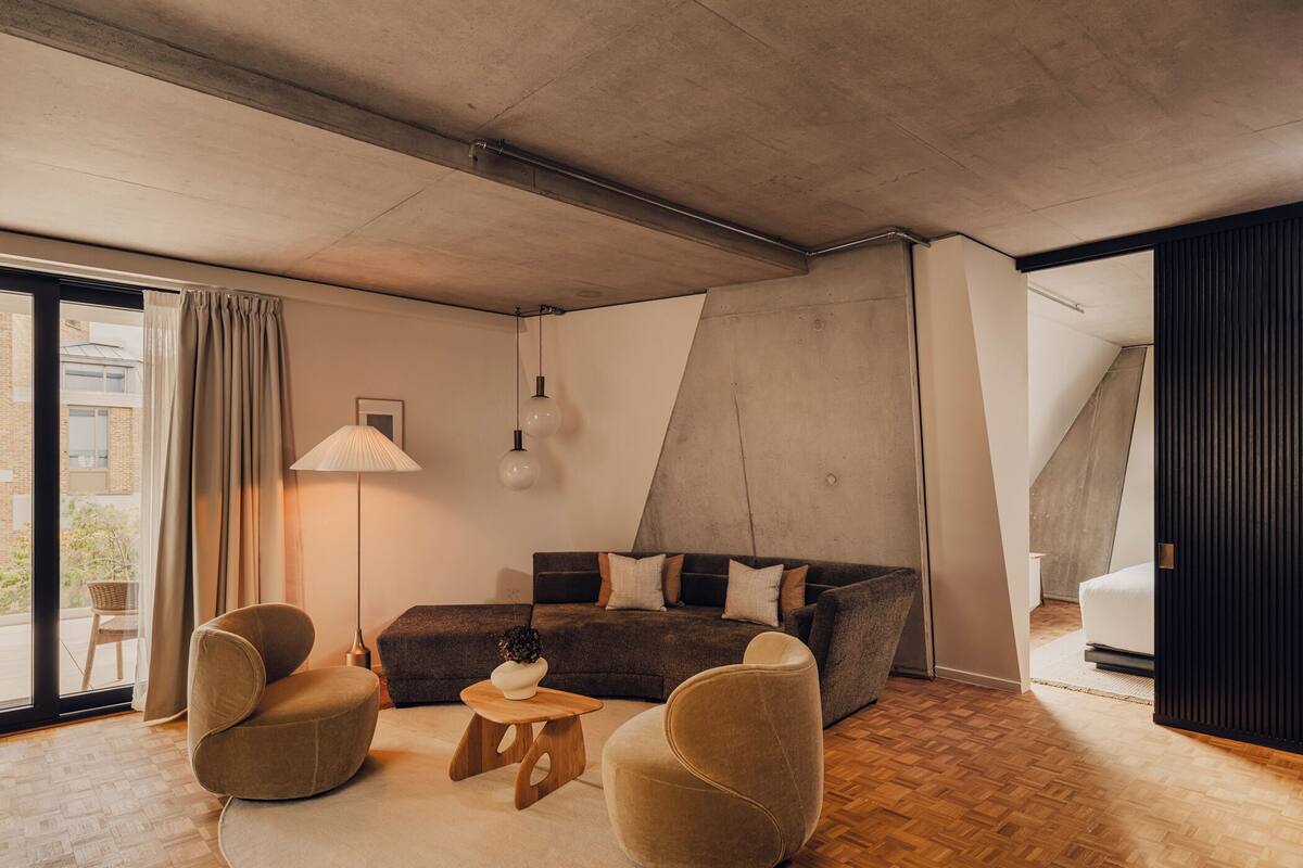 A modern living room with a sofa, two armchairs, a small wooden table, and a floor lamp.