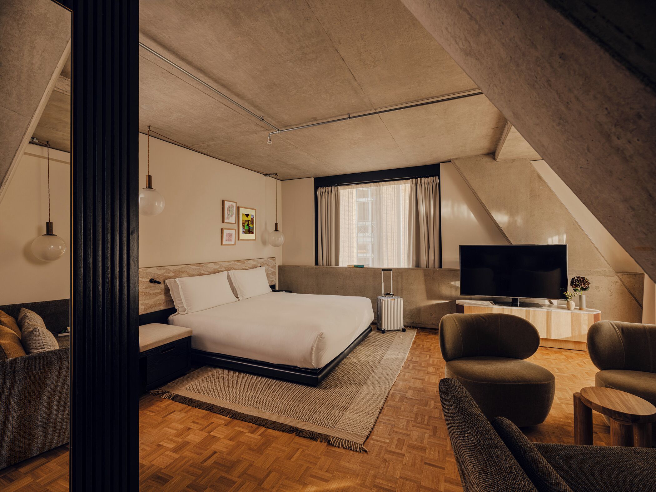 Une chambre d’hôtel moderne avec un grand lit, une télévision, un canapé et une petite table.