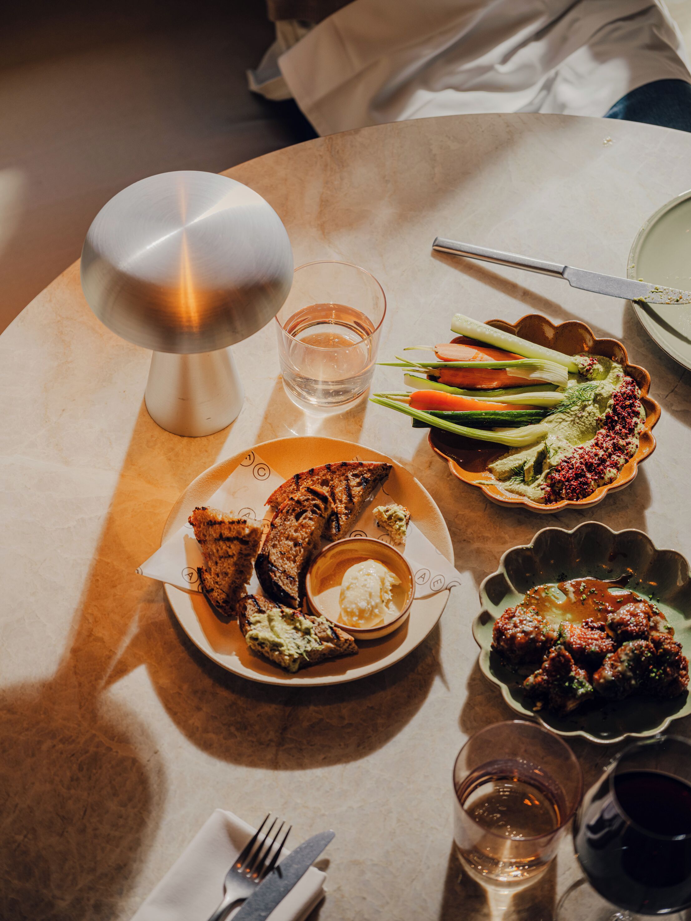 A dining table with a variety of dishes, including grilled meat, vegetables, and a small bowl of sauce.