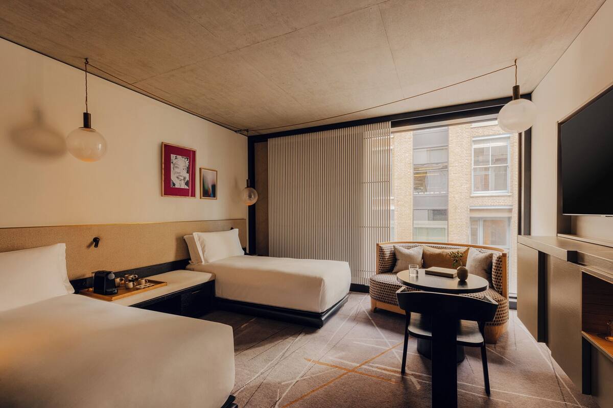 A hotel room with two beds, a sofa, a table, and a TV.