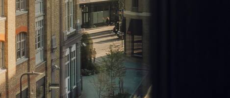 A multi-story urban building with a mix of brick and glass facades, a visible street with pedestrians, and a bicycle parked outside.
