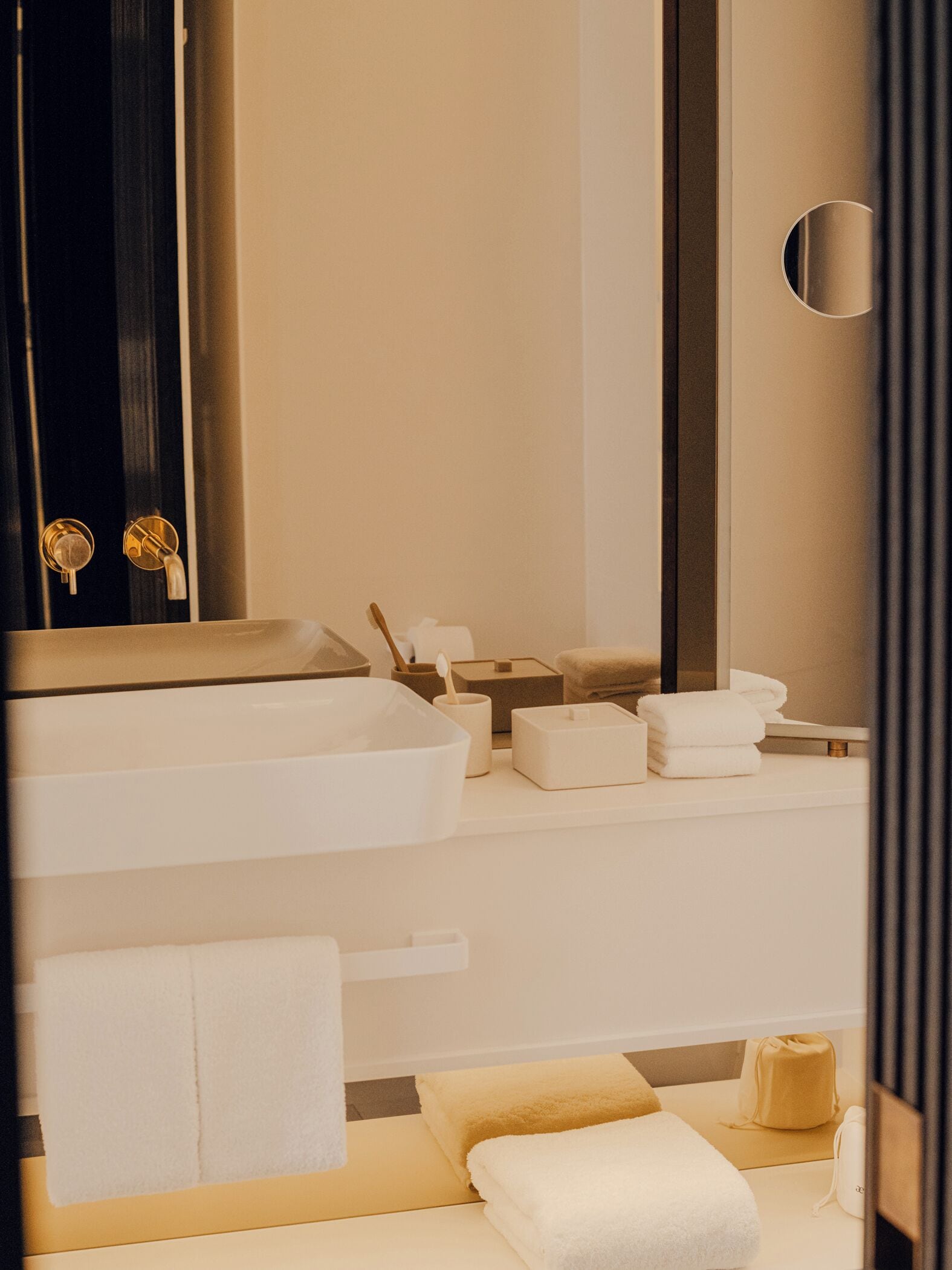 A modern bathroom with a large sink, a mirror, and a towel rack.