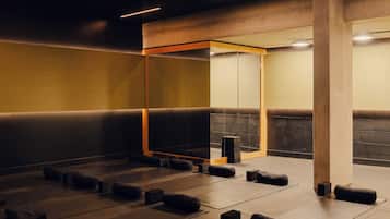A modern, dimly lit room with a geometric ceiling design, wooden accents, and a mirrored wall.