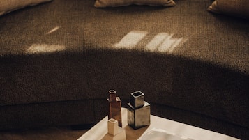 A dark brown sofa with three beige cushions, a small wooden table with a stack of books, and three geometric decorative objects.