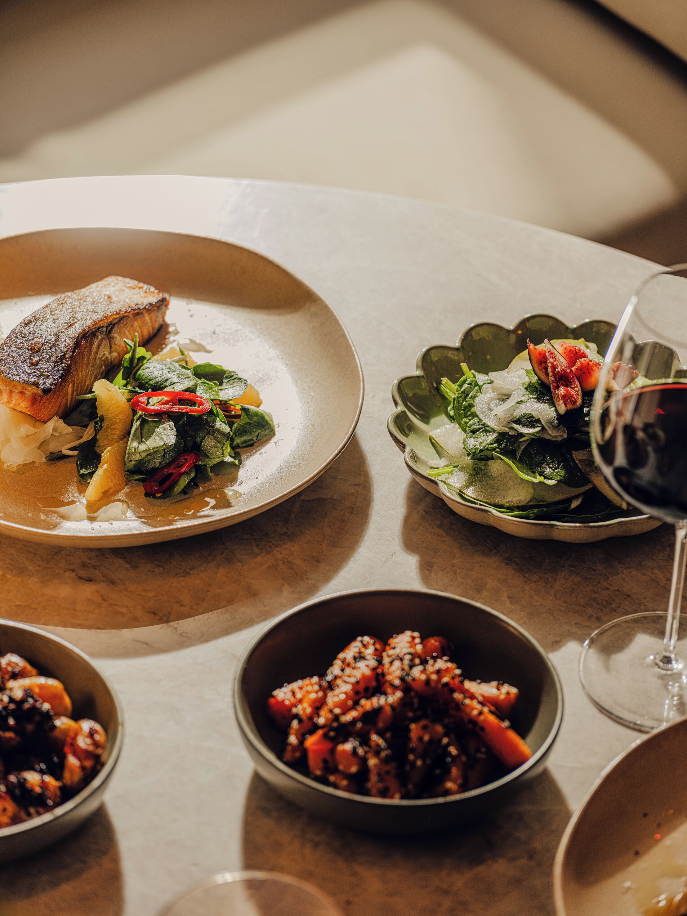 A table with various dishes including a fish, salad, and a bowl of what appears to be a spicy dish.