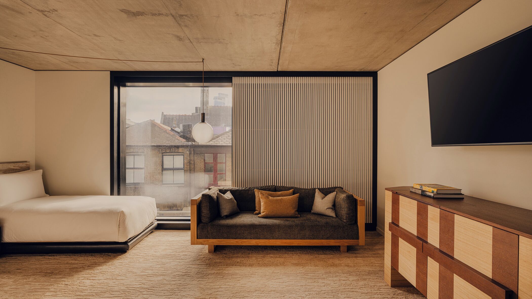 Een moderne hotelkamer met een groot raam, een sofa, een bed en een televisie.