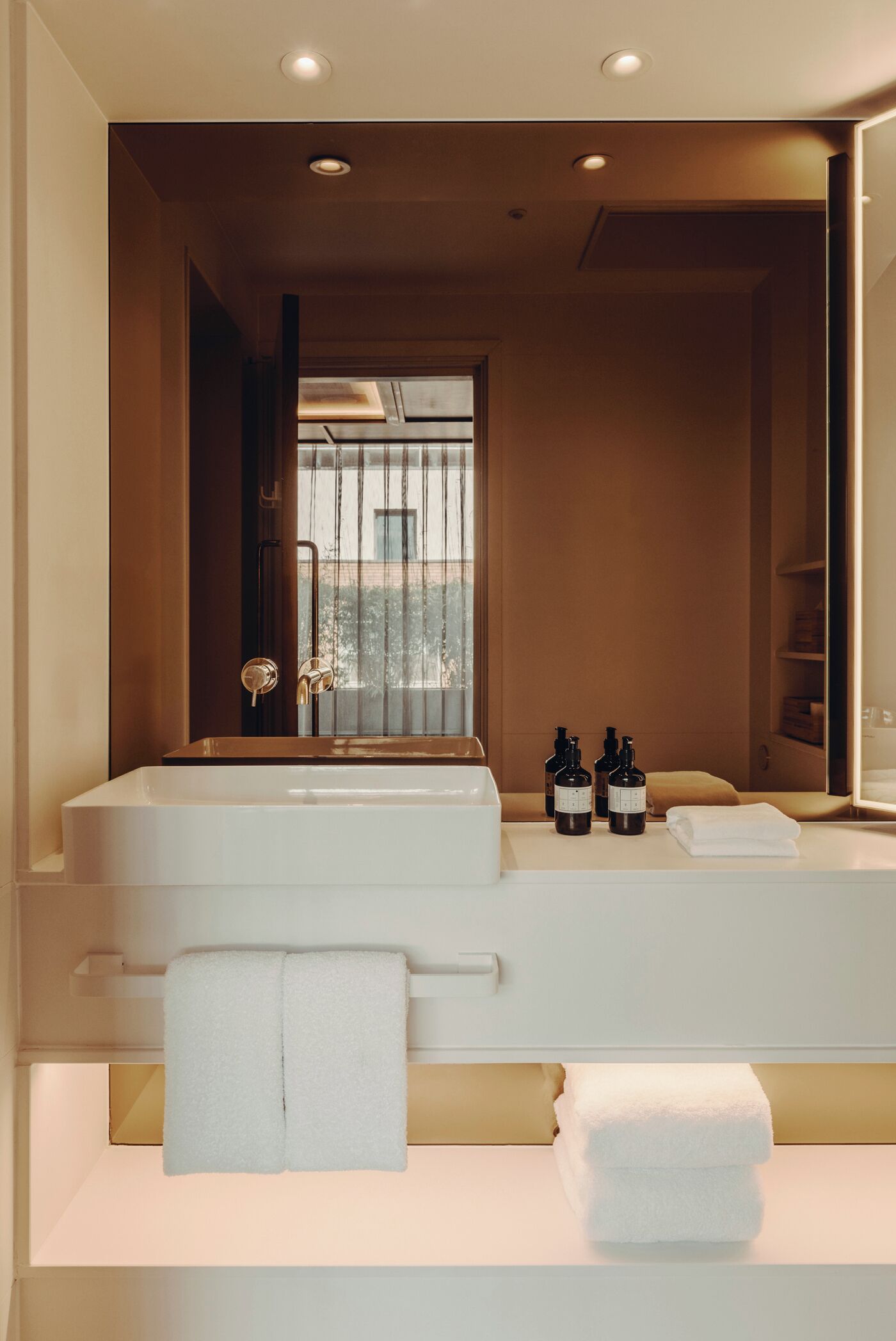 Ein modernes Badezimmer mit zwei Waschbecken, einem großen Spiegel und Blick ins Freie durch ein Fenster.