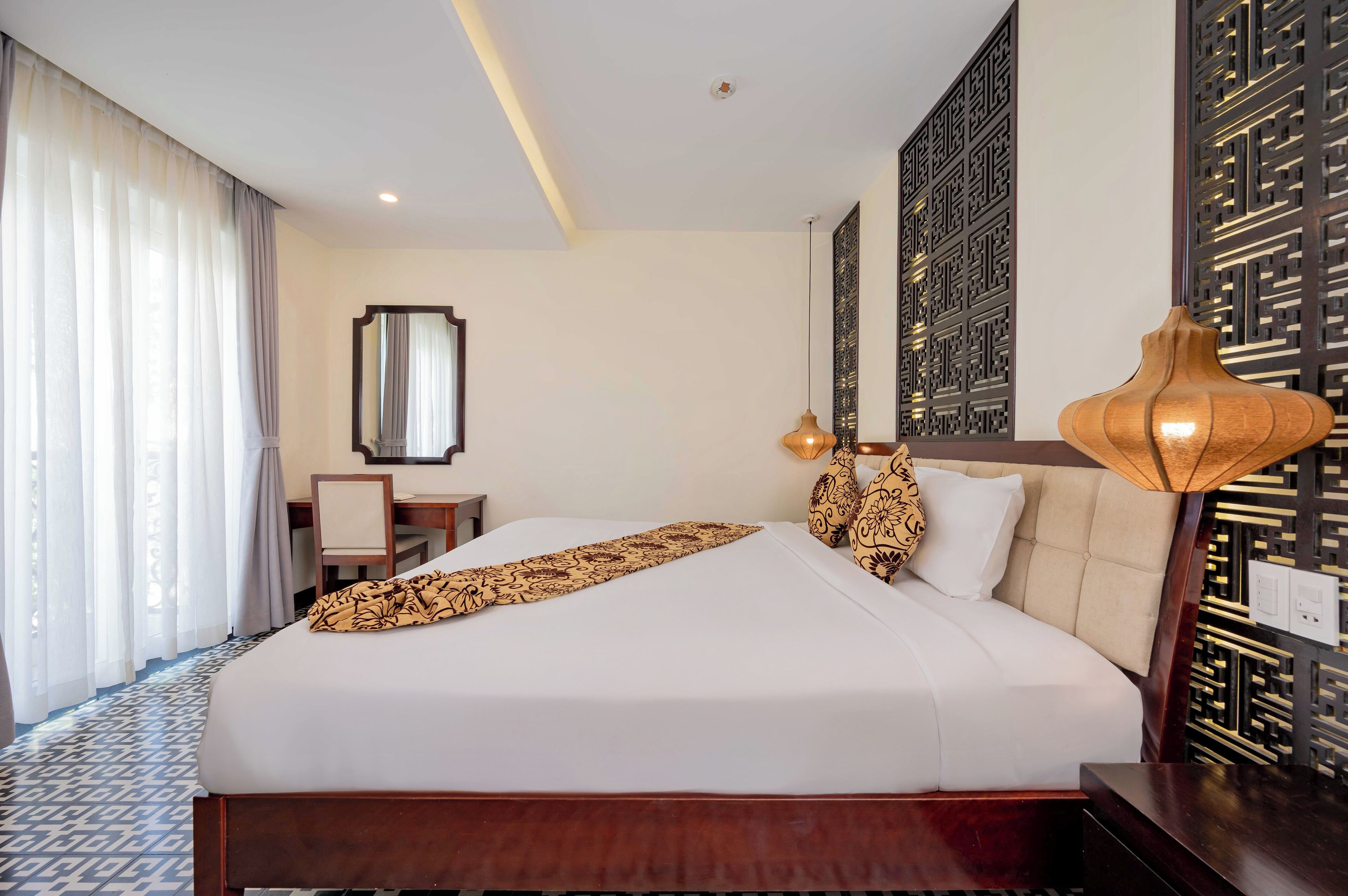 A hotel room with a large bed, a desk, and a chair.