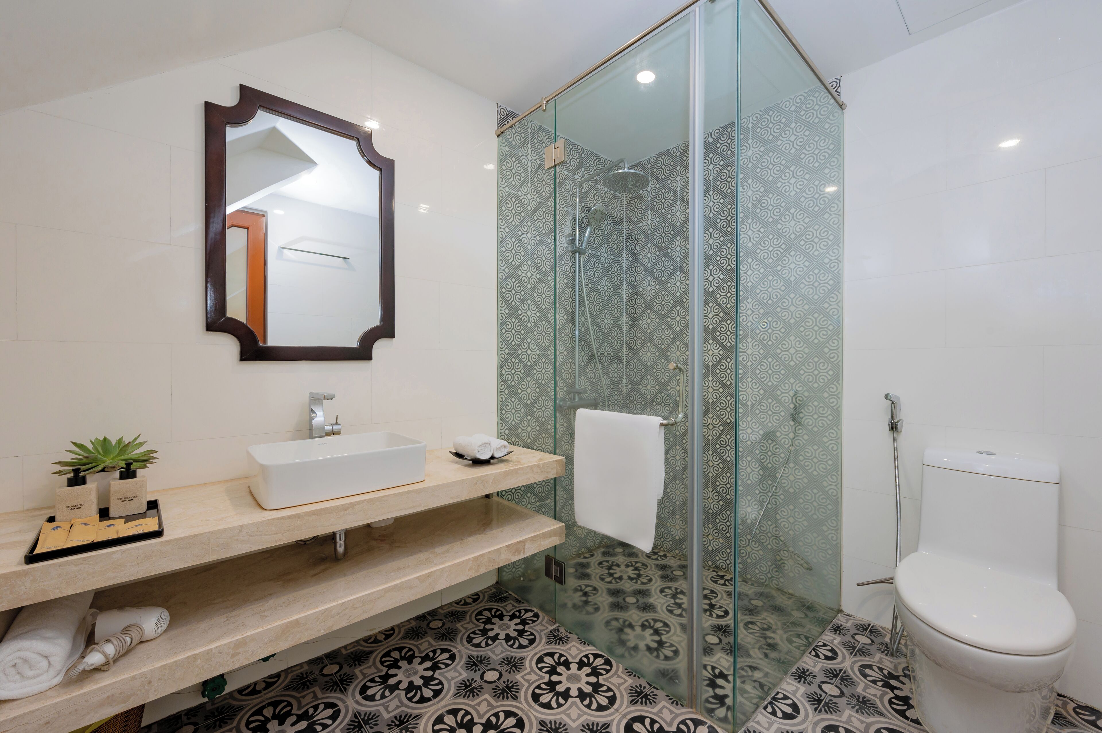 A modern bathroom with a glass-enclosed shower, a white sink, and a toilet.