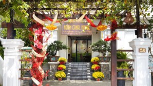 The entrance of Hoian Canal House with a wooden pergola, red and yellow flowers, and a signboard. - Hoi An Canal House Riverside By Haviland (Da Nang)