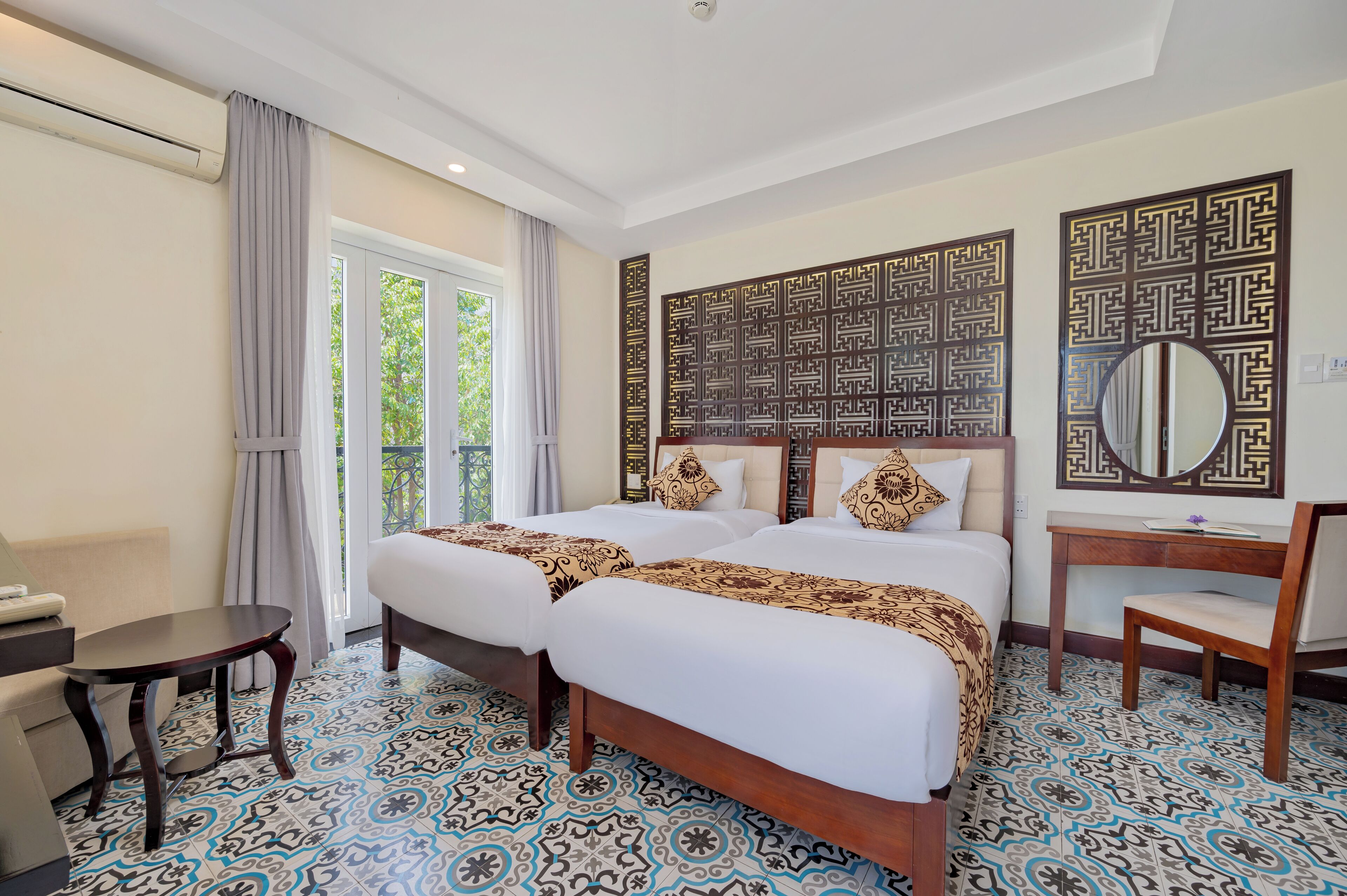 A hotel room with two beds, a desk, a chair, and a large window.