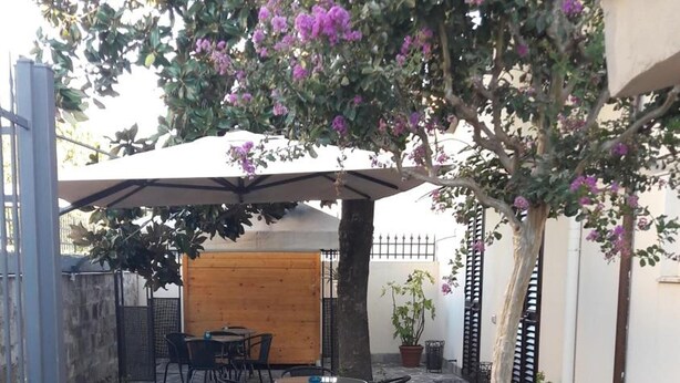 An outdoor patio with stone flooring, surrounded by potted plants and a wooden pergola. - Florence Stadium B&B (Florence)