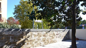 A stone wall with a tree in the foreground and a street sign in the background. - Florence Stadium B&B (Florence)