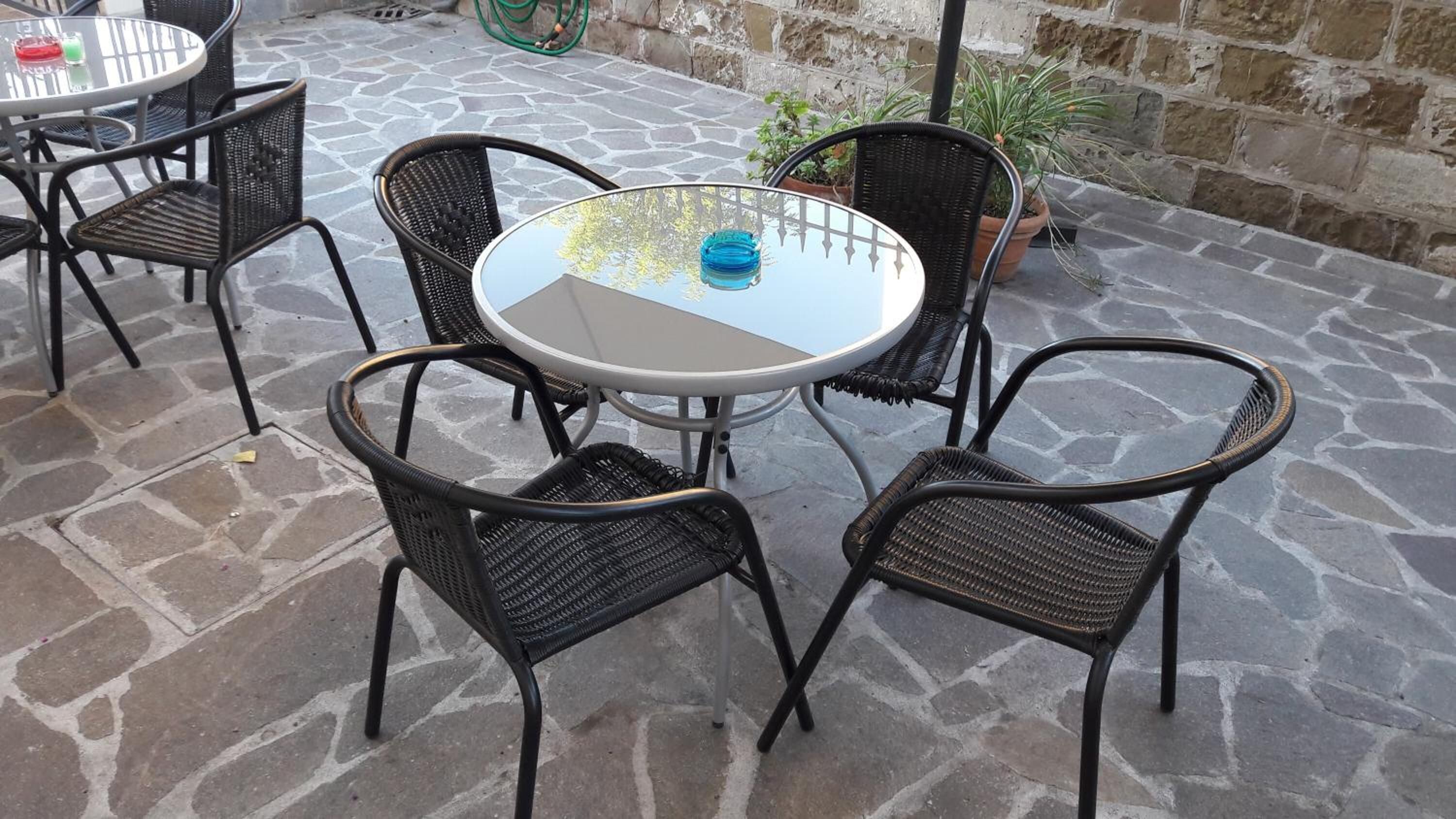Ein runder Tisch mit Glasplatte, umgeben von vier Korbstühlen.