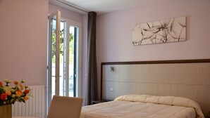 A hotel room with a bed, a chair, a table with a vase of flowers, a window with curtains, and a wall art piece. - Florence Stadium B&B (Florence)