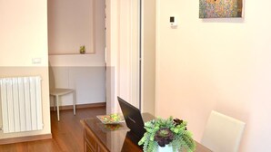 A dining area with a wooden table, white chairs, a potted plant, and a painting on the wall. - Florence Stadium B&B (Florence)