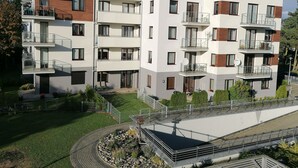 A multi-story residential building with balconies, a landscaped garden, and a pedestrian bridge. - Family Homes - Apartamenty Bursztynowe (Wladyslawowo)