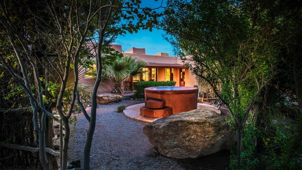 A courtyard with a hot tub, large rocks, and a building with a tiled roof. - Sierra Grande, A Ted Turner Retreat (Truth or Consequences)