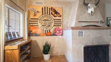 A room with a mural of butterflies and flowers, a wooden shelf with brochures, a potted plant, and a bull skull on the wall.