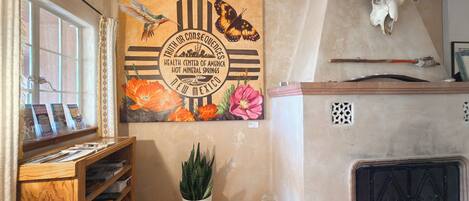 A room with a mural of butterflies and flowers, a wooden shelf with brochures, a potted plant, and a bull skull on the wall.