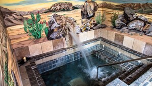 A hot tub with a desert mural backdrop, surrounded by rocks and cacti. - Sierra Grande, A Ted Turner Retreat (Truth or Consequences)