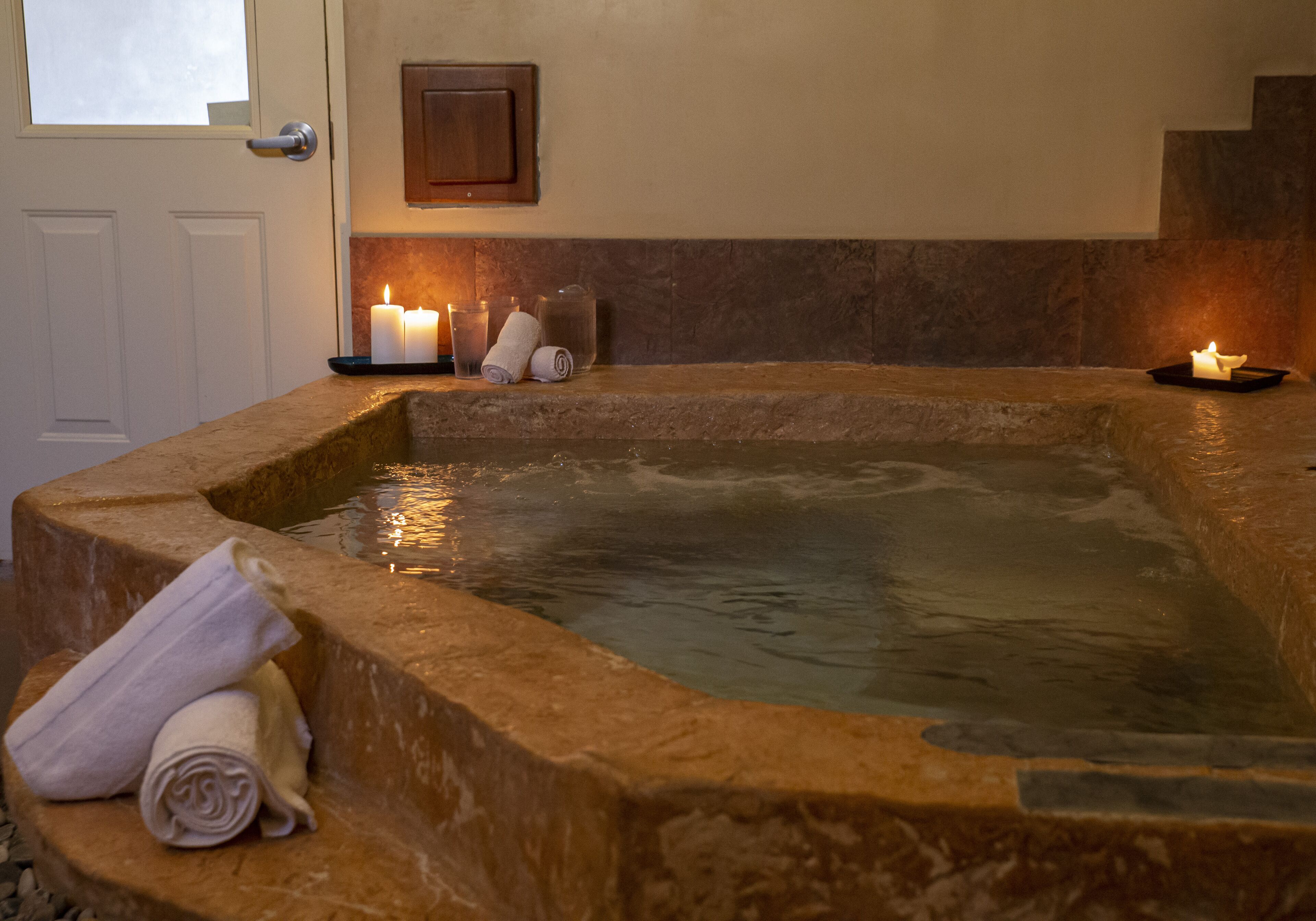 A stone hot tub with candles and towels.