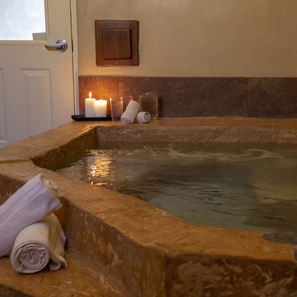 A stone hot tub with candles and towels.