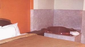 A hotel room with a bed, a nightstand, and a bathtub. - A Victory Inn East Dearborn (Detroit)