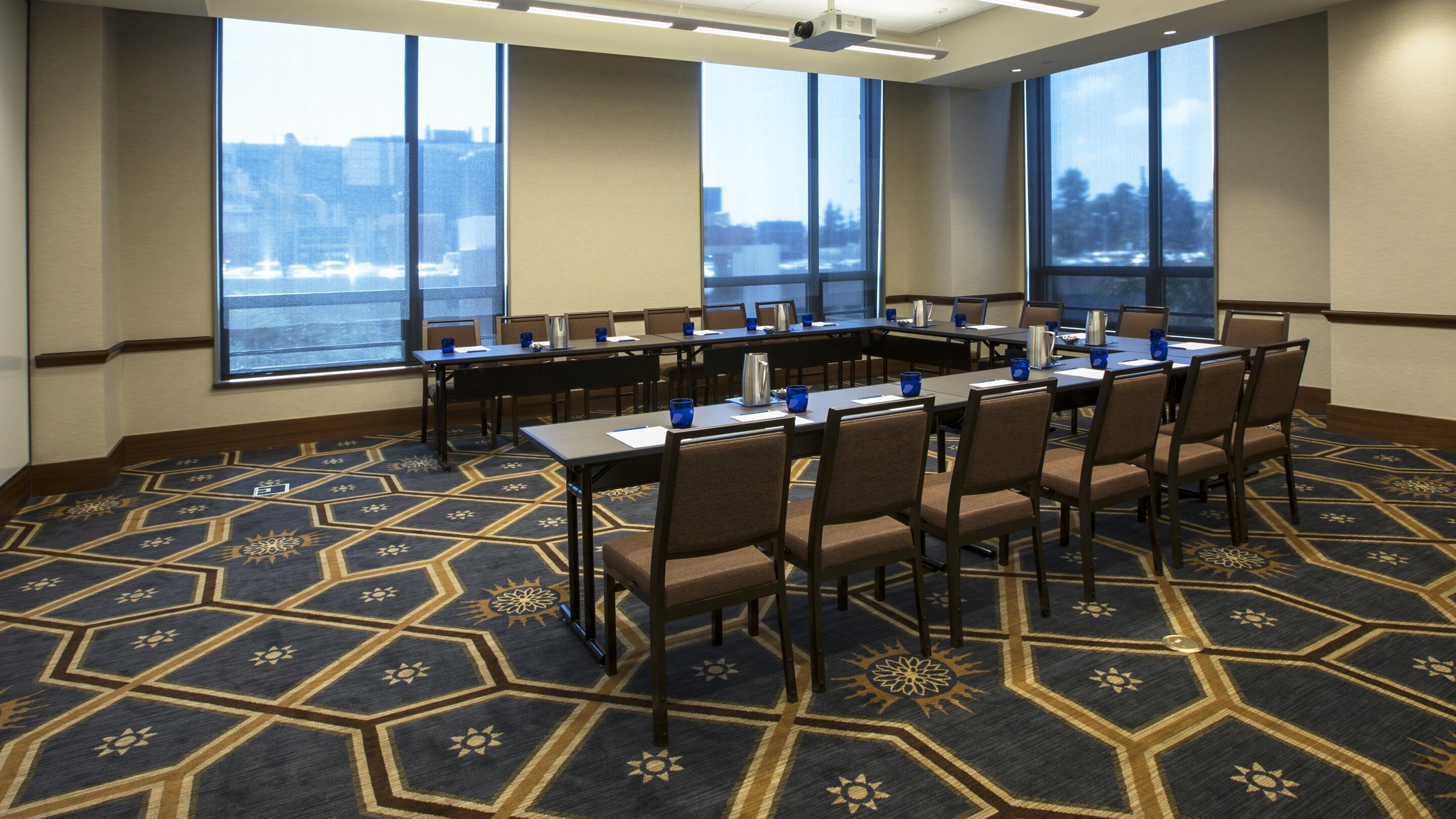 A conference room with a large table, chairs, and a carpeted floor.