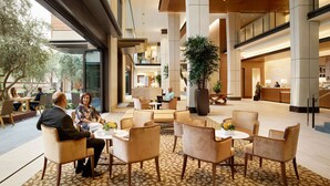 A spacious lobby with a reception desk, comfortable seating areas, and a large potted plant. - Luskin Hotel (Los Angeles)