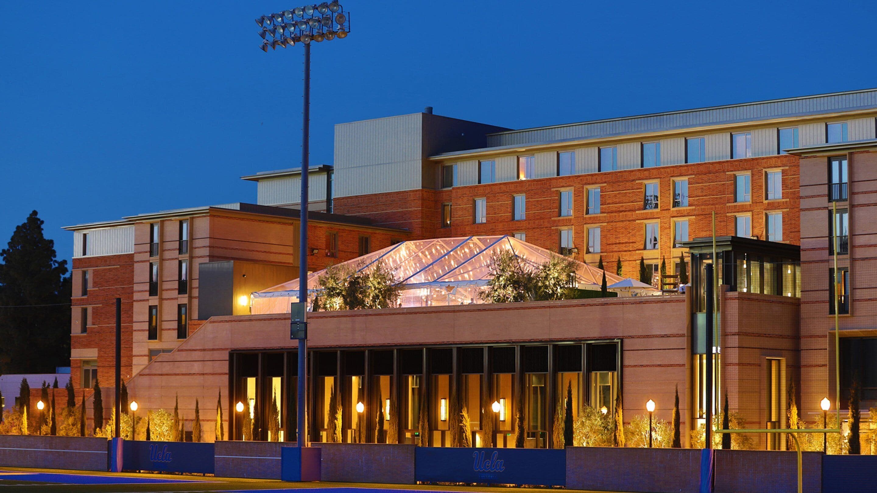 A modern hotel with a prominent glass atrium, multiple floors, and a well-lit facade.