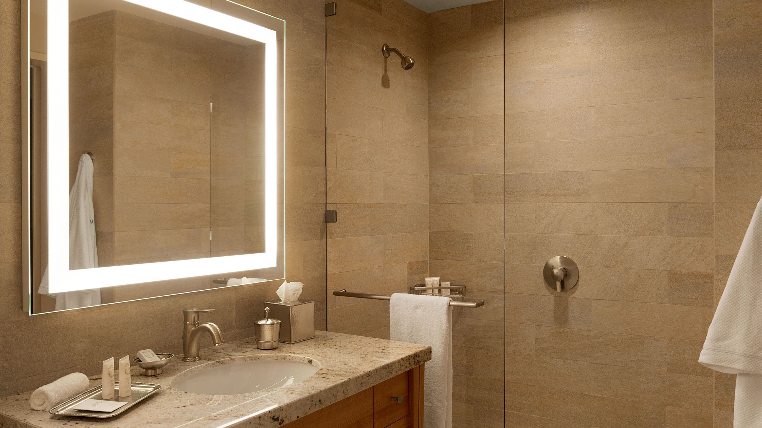 Une salle de bain avec un grand miroir, un lavabo, une douche et un porte-serviettes.