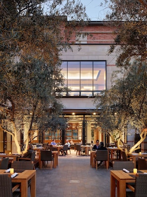 An outdoor dining area with tables and chairs, surrounded by trees.