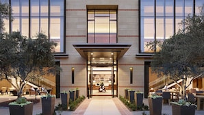 A hotel entrance with a central atrium, outdoor seating, and a staircase leading to the upper floors. - Luskin Hotel (Los Angeles)