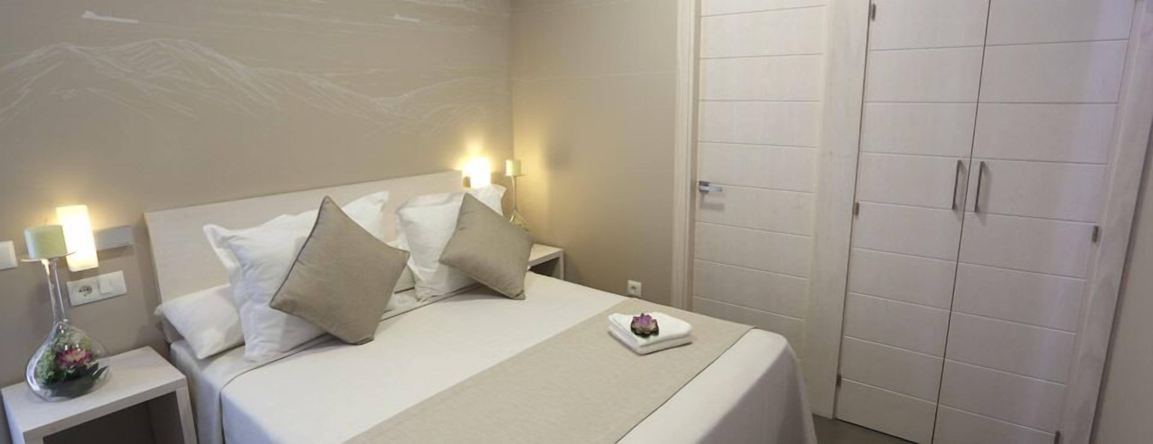 A hotel room with a bed, nightstands, a dresser, and a wardrobe.